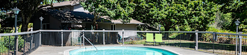 a pool with a fence around it and a house in the background