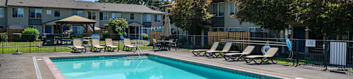A swimming pool surrounded by lounge chairs and trees.