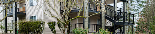 A grey car is parked in a parking lot in front of a two-story building.