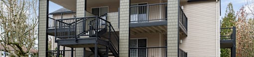 A modern two-story apartment building with a balcony and staircase.