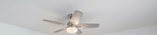 a bedroom with white walls and a ceiling fan