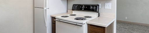 A kitchen with a white stove and refrigerator.