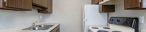 A kitchen with white appliances and brown cabinets.