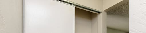 A white closet with a shelf and a door open.