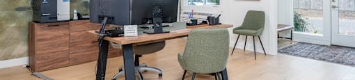 A room with a desk, chairs, and a computer setup.