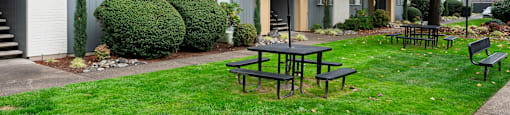 A grey building with a patio table and chairs in front of it.