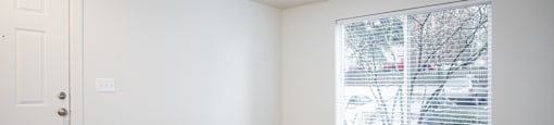A room with a white door and a window with blinds.