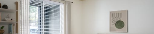 A bedroom with a bed, nightstand, and window with blinds.