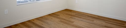 A room with a window and wooden flooring.