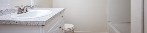 A white bathroom with a sink, toilet, and a mirror.