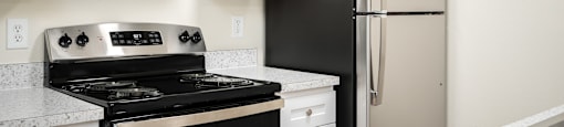 A black stove and refrigerator in a kitchen with white cabinets.