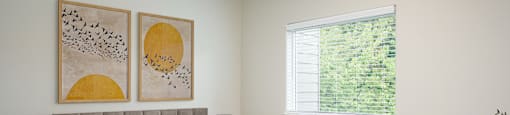 A bedroom with a large bed and two framed pictures on the wall.