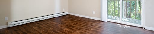 an empty living room with wood floors and a large window