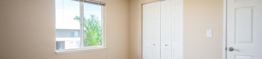 an empty room with carpet and a window and two doors
