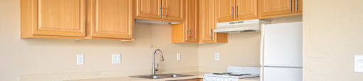 an empty kitchen with wooden cabinets and white appliances