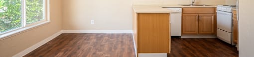 an empty kitchen with wood flooring and a large window