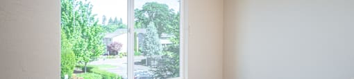 an empty room with a large window and wooden floors