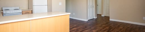 an empty kitchen with wooden floors and a white refrigerator