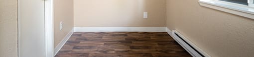 an empty room with wood flooring and a window