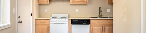 an empty kitchen with white appliances and wooden cabinets