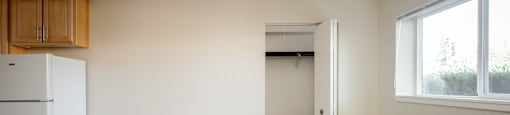 an empty room with a refrigerator and a window