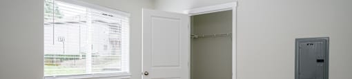 A room with a white door and a window with blinds.