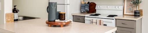 A kitchen with a white countertop and a white fridge.