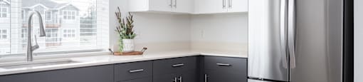 a kitchen with gray cabinets and a stainless steel refrigerator
