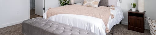 large bedroom with bed, side tables and ottoman