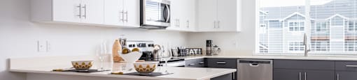 a kitchen with white cabinets, breakfast bar with two stools in front of it