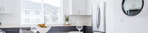 a kitchen with white cabinets, large window and breakfast bar
