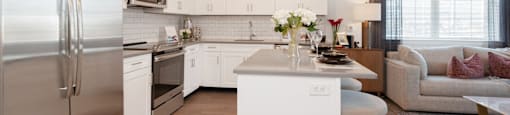 a kitchen and living room with stainless steel appliances and white cabinets