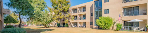 an apartment building with a lawn and trees in front of it