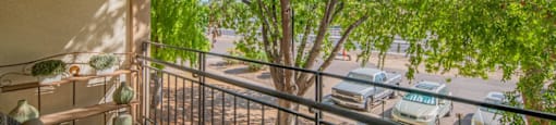 a balcony with a view of a tree and cars on the street