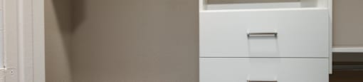 a walk in closet with white shelves and drawers and