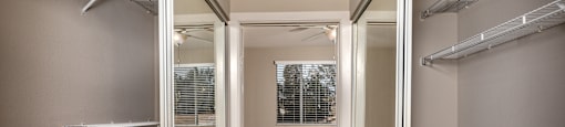 a walk in closet with mirrored mirrored closet doors and a window