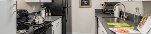 A kitchen with black appliances and white cabinets.