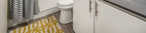 A bathroom with a white toilet, a sink, and a shower with a grey and white curtain.