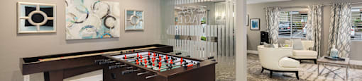 A pool table is in the middle of a room with a chair and a painting on the wall.