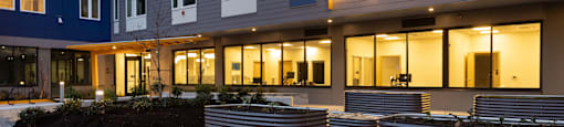 an outdoor courtyard of an apartment building with benches and grass at The Aries at Bitter Lake Apartments, Seattle, 98133
