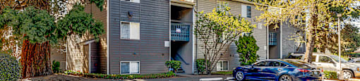 A blue car is parked in a parking lot in front of a building.
