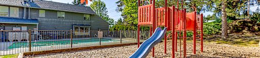 A playground with a red swing set and a blue slide.