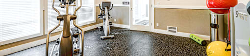 A room with a treadmill, exercise bike, and other fitness equipment.