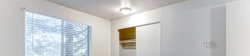 A room with a carpeted floor and a window with blinds.