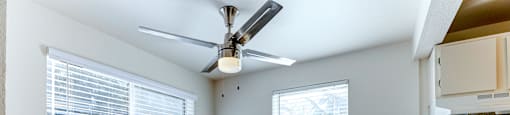 A room with a ceiling fan and a window with blinds.