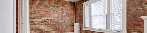 A room with a brick wall and a window.