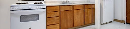 A kitchen with a white stove and wooden cabinets.