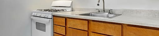 A kitchen with a white stove and wooden cabinets.