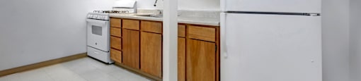 A kitchen with white appliances and wooden cabinets.