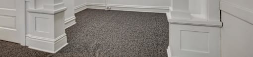 A room with white walls and a grey carpet.